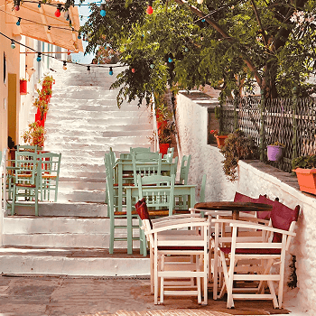 Charming outdoor seating area in Andros with colorful chairs and lush greenery.