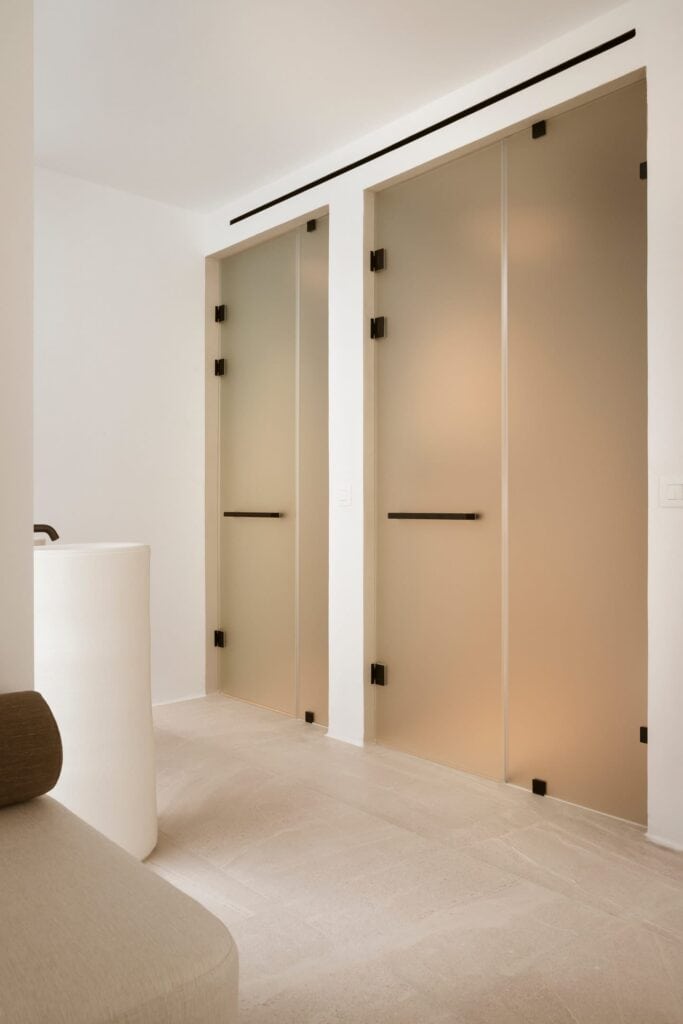 Elegant glass doors with black hinges in a stylish hotel room.