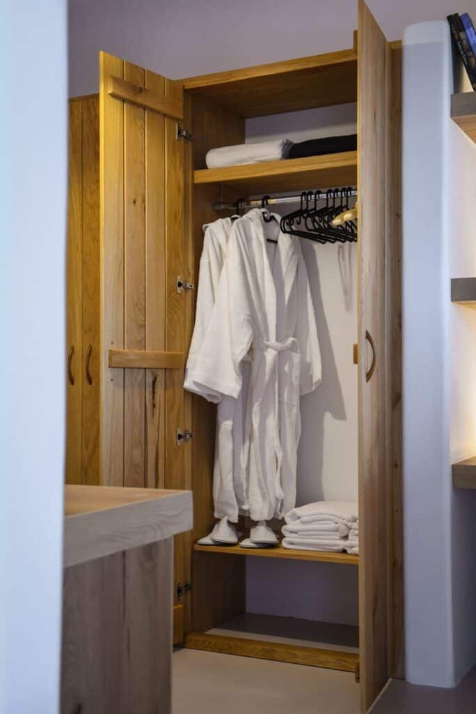 Closet in executive suite with robes, towels, and wooden shelves at Mr and Mrs White Hotels Cyclades.