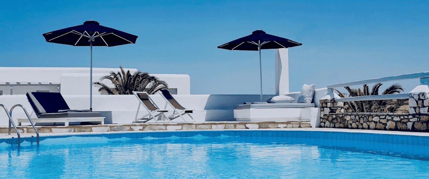 Elegant poolside scene with sun loungers and umbrellas at Mr and Mrs White Hotels Cyclades.