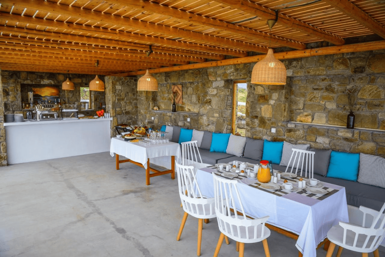 Stylish outdoor restaurant with stone walls, cozy cushions, and wooden ceiling.