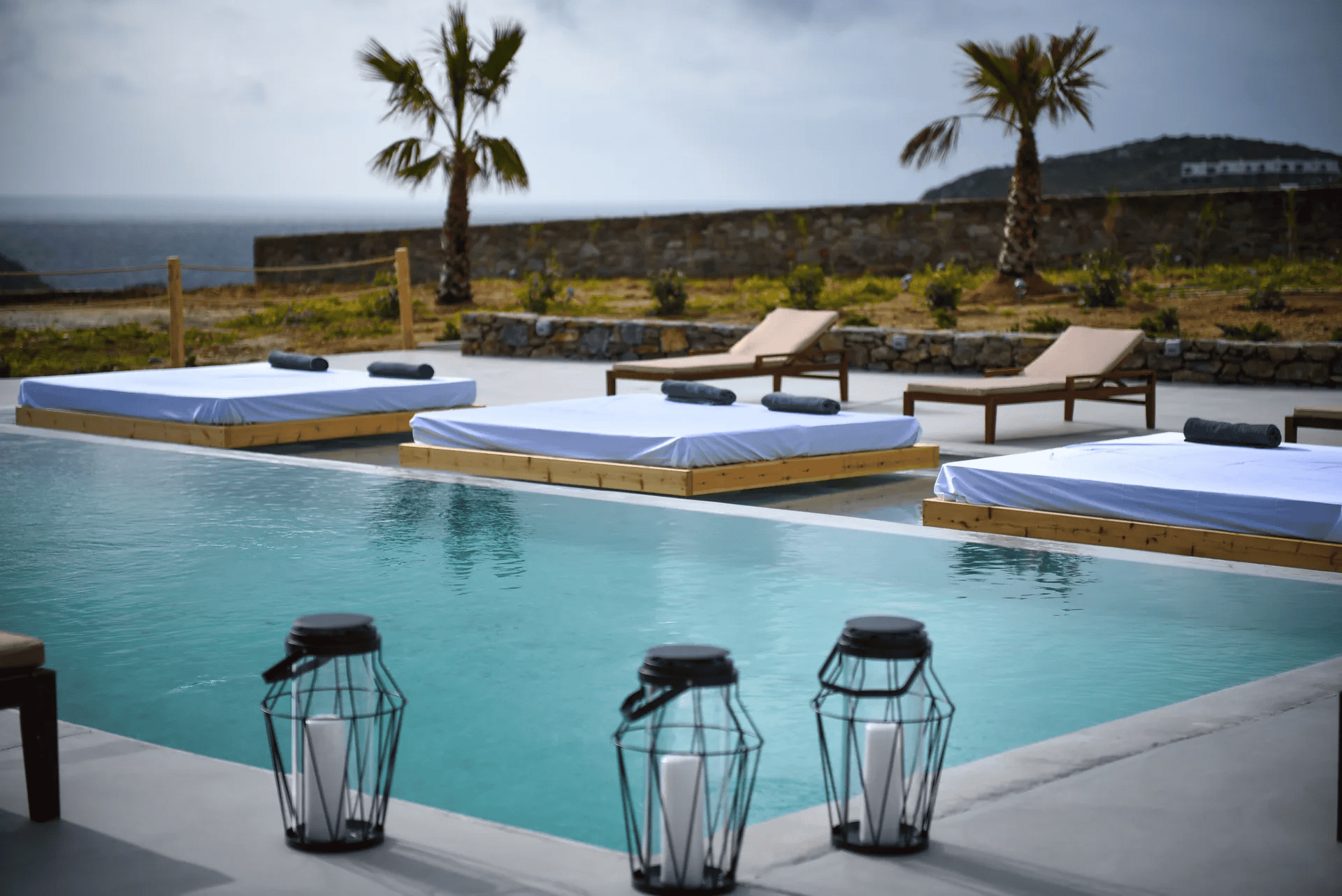 Poolside lounge with sunbeds and ocean view at Myconian Crown, part of Mr and Mrs White Hotels Cycla.