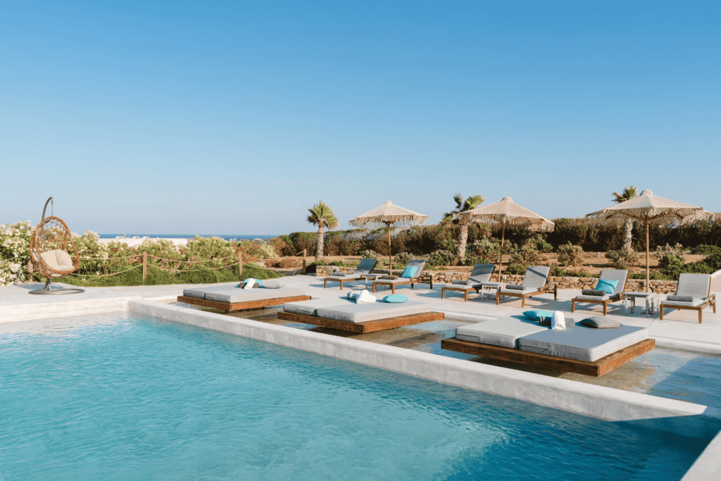 Poolside lounge with sunbeds and umbrellas at Myconian Crown, Cyclades.
