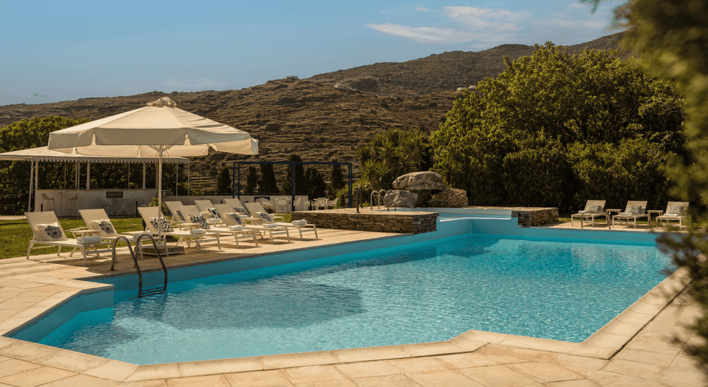 Scenic outdoor pool with sun loungers and umbrellas at Mr and Mrs White Hotels Cyclades.