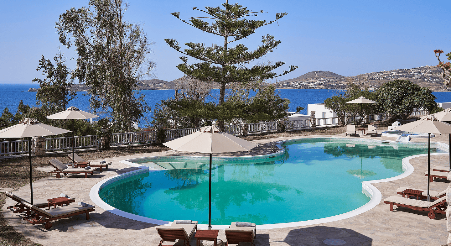 Scenic view of High Mill Paros with pool, trees, and sea in the background.