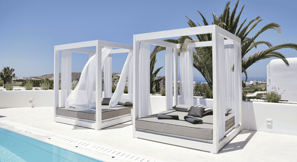 Elegant poolside cabanas with white curtains at Livin Mykonos, perfect for relaxing in the Cyclades.