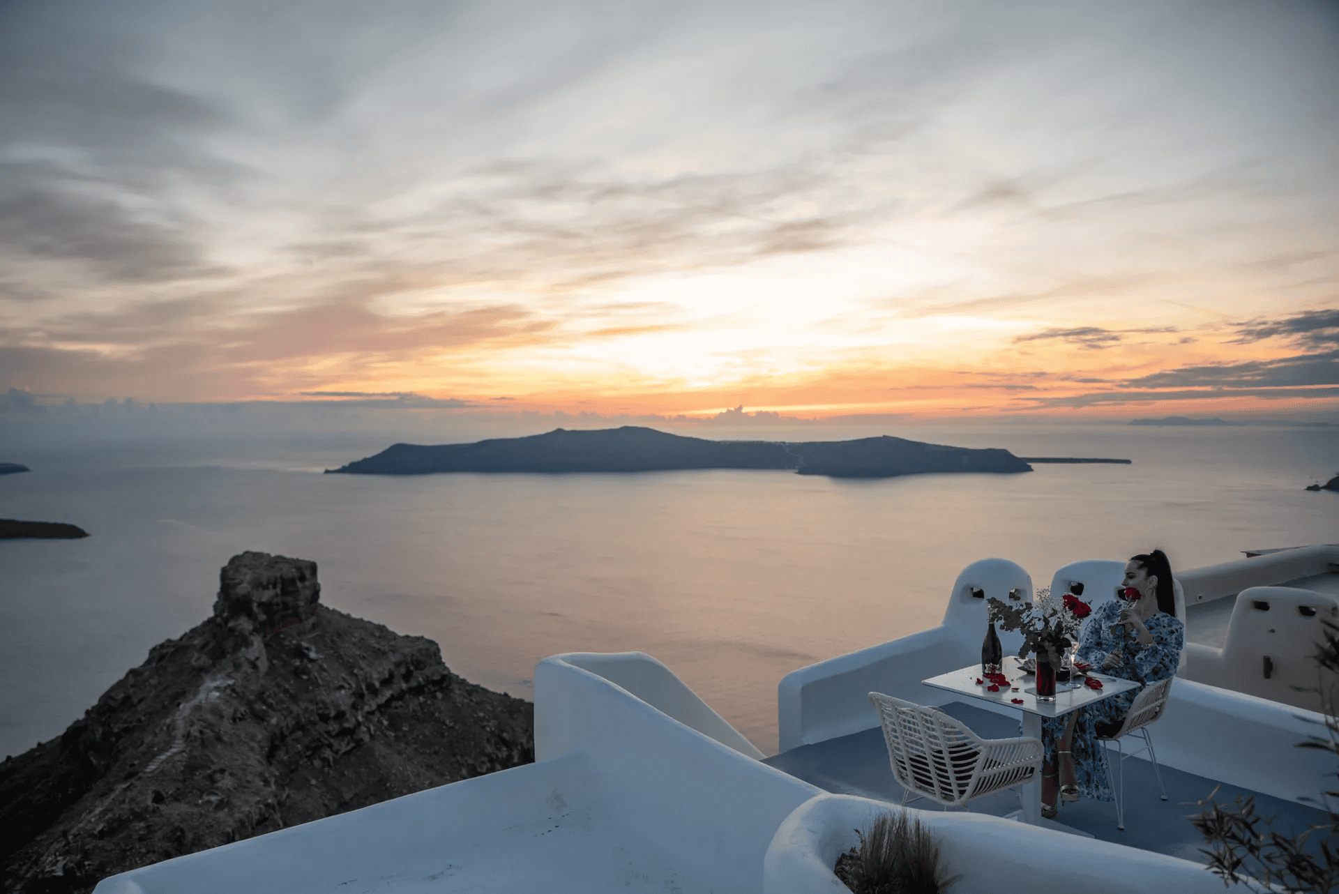 Beautiful sunset view over Santorini caldera with white architecture and romantic dining setting.