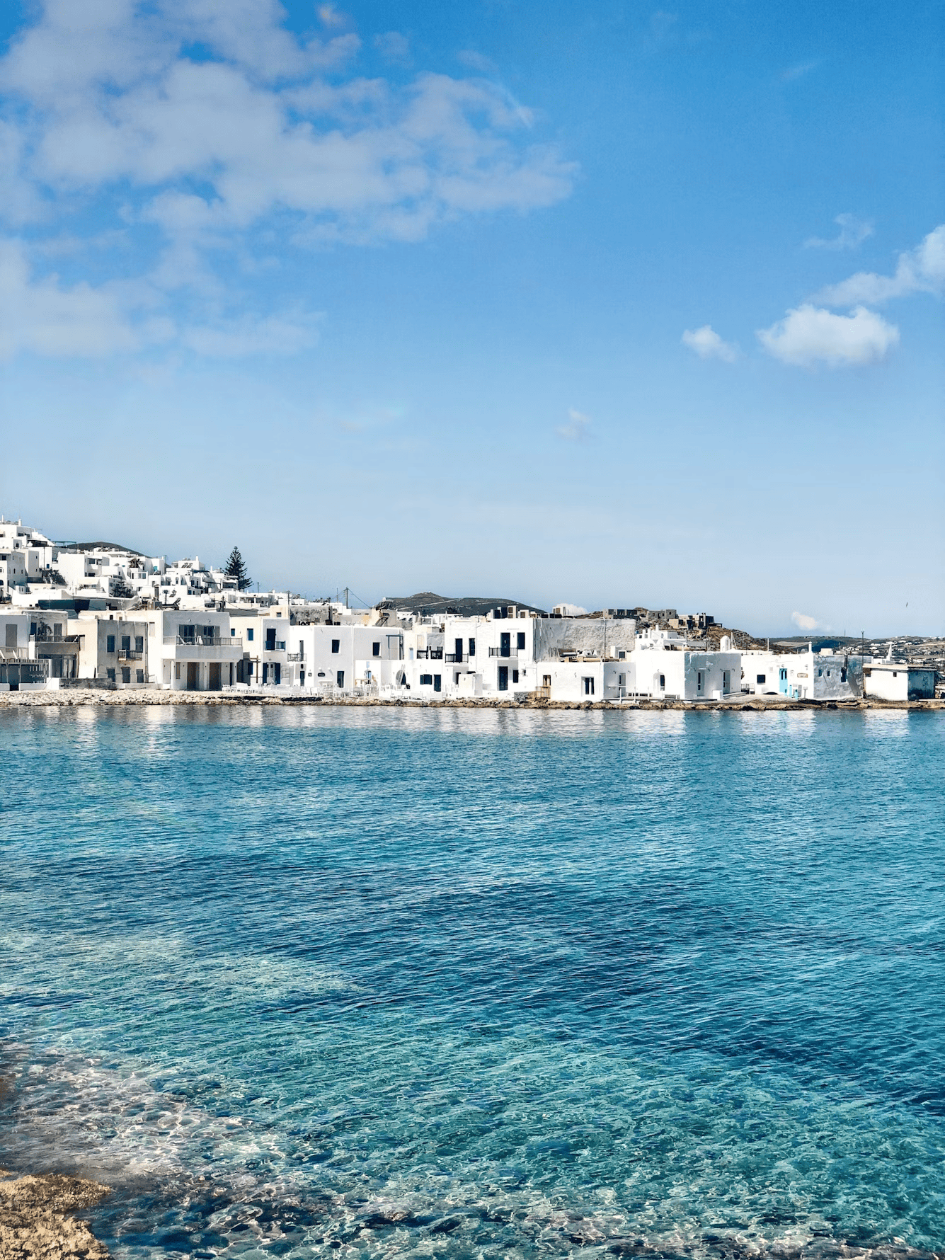 Paros island coastline with whitewashed buildings and clear blue waters, perfect for relaxing holida.
