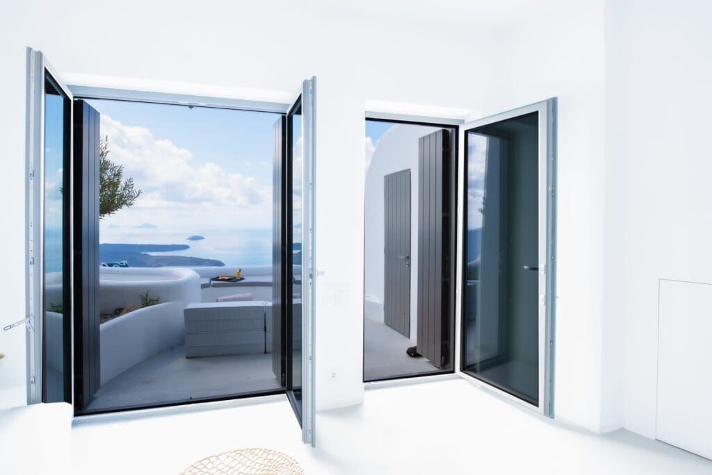 Sea view villa with indoor pool, open doors to a stunning ocean vista, perfect for luxury Cyclades a.