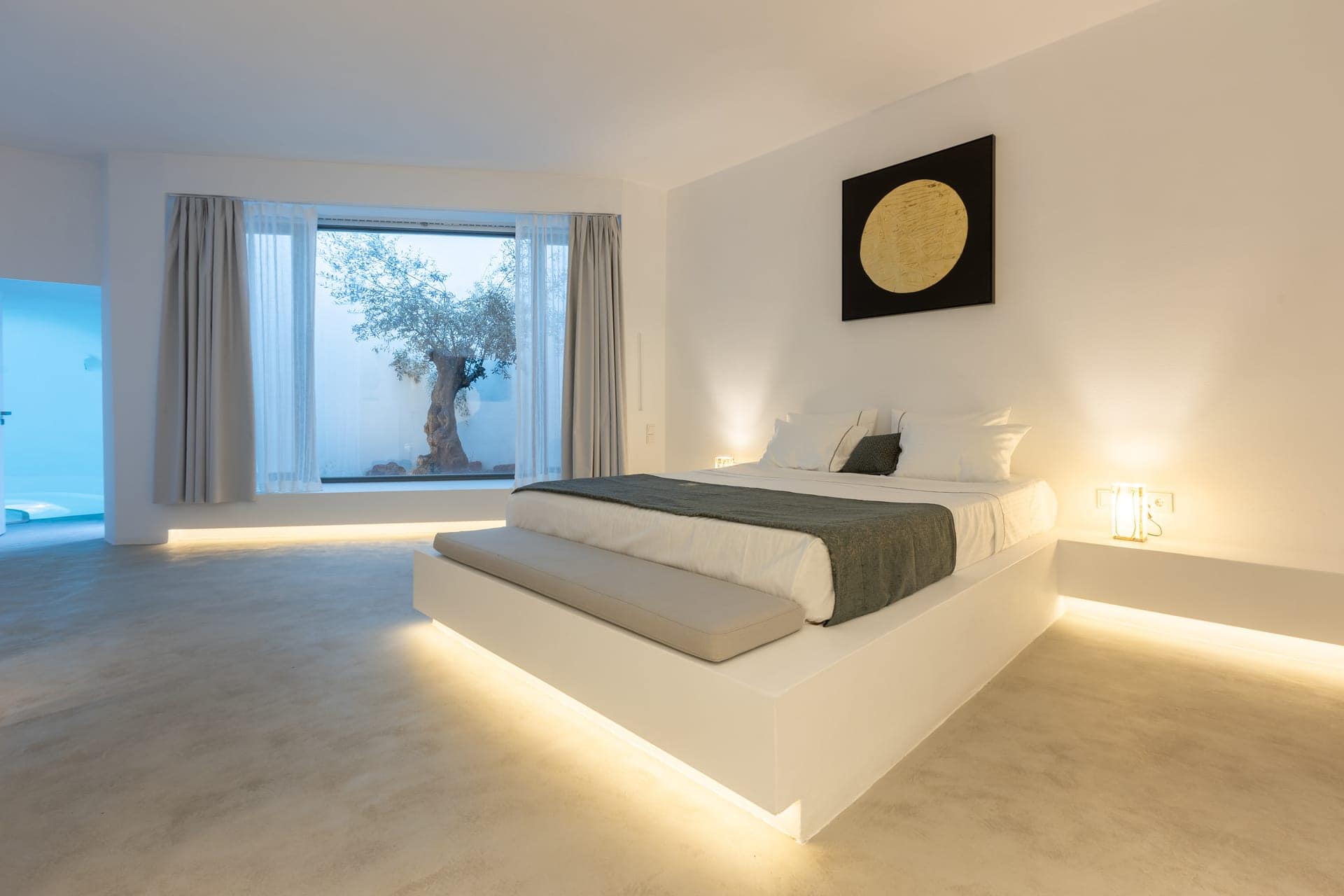 Elegant bedroom with white decor, large window, and cozy bed at Heavens Edge Villa.