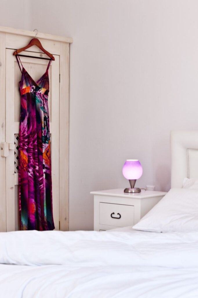 Elegant bedroom with colorful dress hanging on a wooden wardrobe.