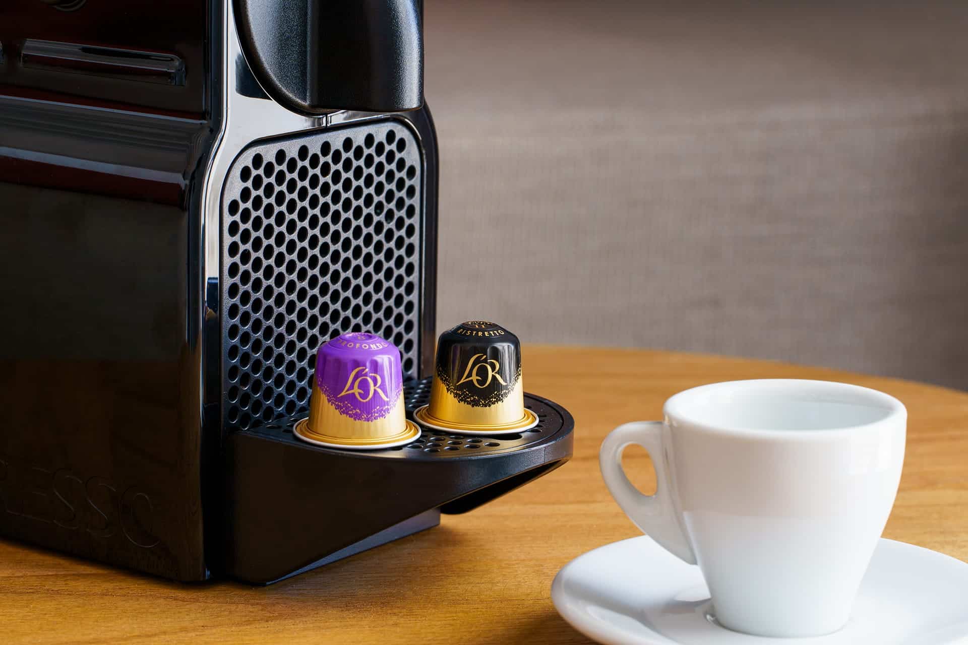 Modern coffee machine with capsules and white ceramic cup.