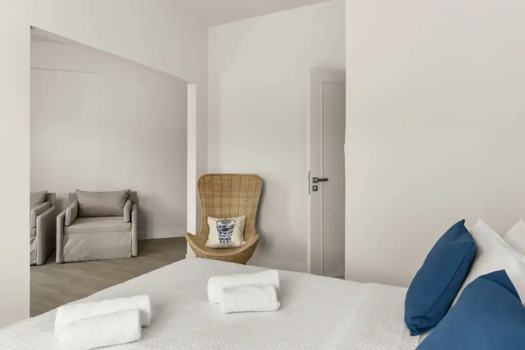 Spacious hotel suite with modern decor, comfortable bed, and relaxing seating area in the Cyclades.