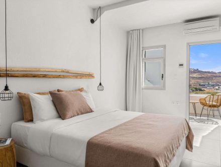 Comfort triple room with modern decor, cozy bedding, and scenic balcony views in the Cyclades. Perfe.