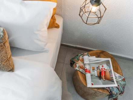 Comfortable bedroom with cozy bedding and a side table with magazines and a decorative lamp.