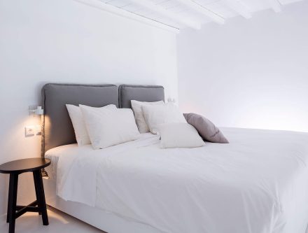 Elegant hotel room in the Cyclades with white linens and minimalist design.