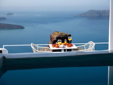Elegant villa balcony overlooking the Aegean Sea with outdoor dining setup.
