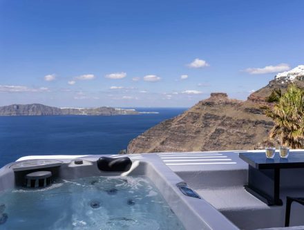 Honeymoon suite with outdoor jetted tub overlooking Santorini's caldera, perfect for romantic getawa.