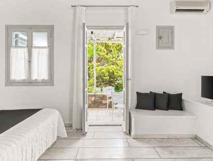 Cozy bedroom with garden view, white walls, and natural light in Mr and Mrs White Hotels Cyclades.