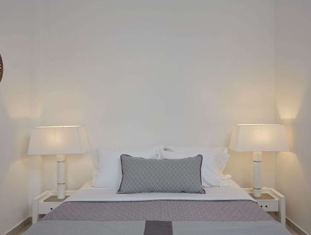 Double room with minimalist design, white walls, and soft lighting in Cyclades hotel.