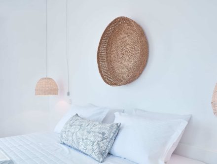 Modern hotel room with wicker wall art and soft lighting, no view.